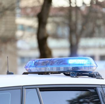 a close-up view of a police vehicle with blue lights patrolling near a public park with the windows and doors closed a close up view of a police vehicle with blue lights patrolling near a public park with the windows and doors closed