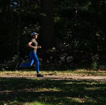 woman running along a trail with a background of dark trees