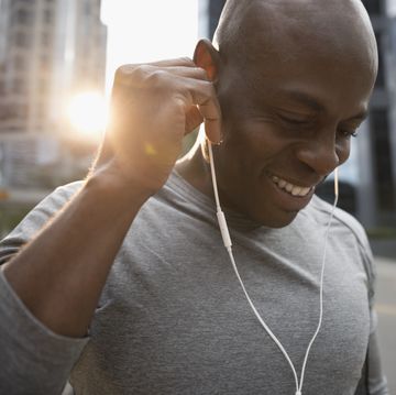 how to start running Close up smiling male runner listening to music with earbud headphones on urban street