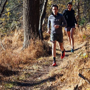 two people running on a trail in the fall two people running on a trail in the fall