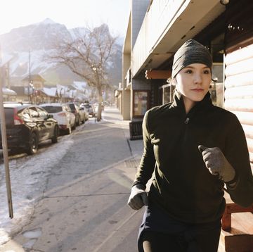 Focused teenage girl running along sunny winter sidewalk
