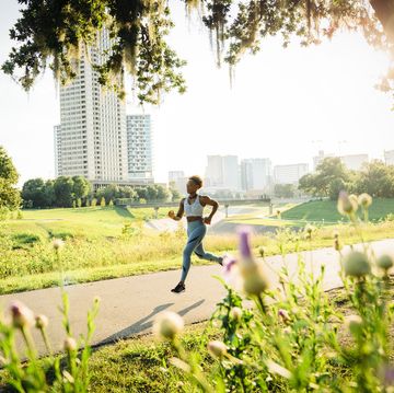 woman running on path in park beyond wildflowers