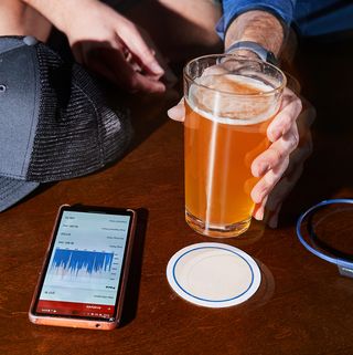 running hat, fitness tracker app, headphones and glass of beer on coffee table
