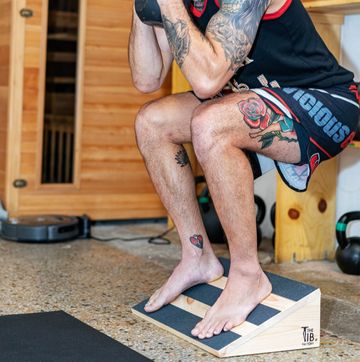a man does a kettlebell squat using a slant board