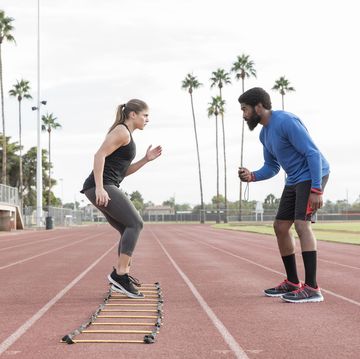 trainer watching woman running ladder