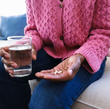 woman holds capsules and glass of water