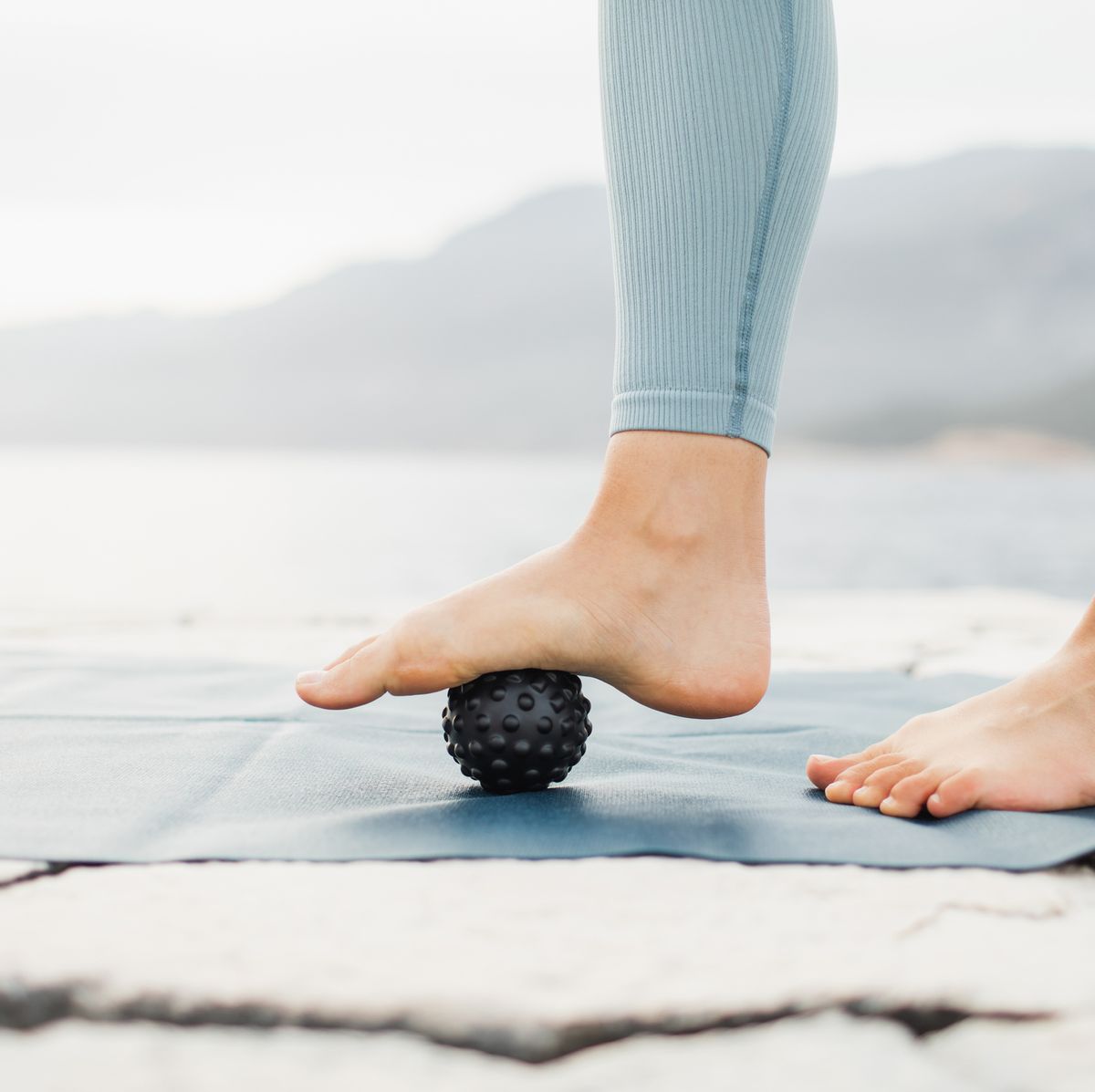 Woman massaging foot with black massage ball. Roller massager, self massage and healthy lifestyle plantar fasciitis