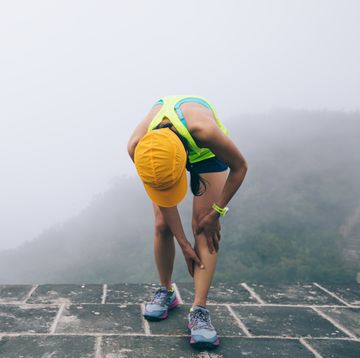woman trail runner hold her sports injured legs at the top of mountain woman trail runner hold her sports injured legs at the top of mountain